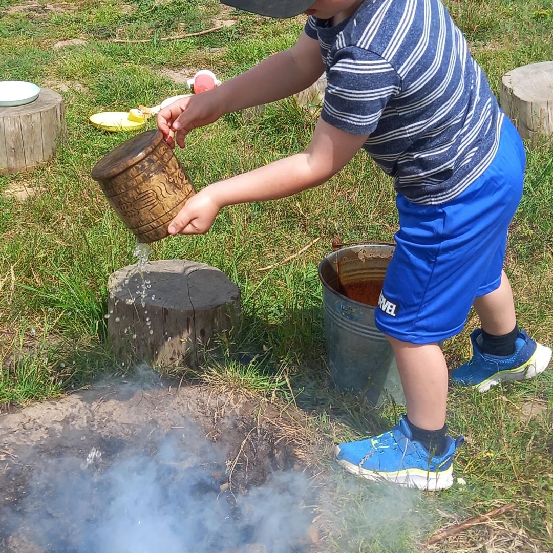 A child standing proudly on a tree stump in the centre's meadow